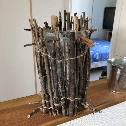 Branches réunies avec de la ficelle de jute fine en cercle pour servir de poubelle. Un sac en plastique à l'intérieur
