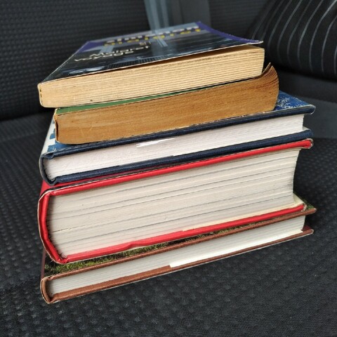a pile of 5 books sitting on a seat in a car