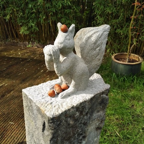 foto einer eichhörnchen-skulptur, auf der einige haselnüsse liegen