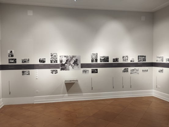 Foto zeigt eine Reihe von Schwarz-Weiß-Fotos, die an einer weißen Wand hängen.