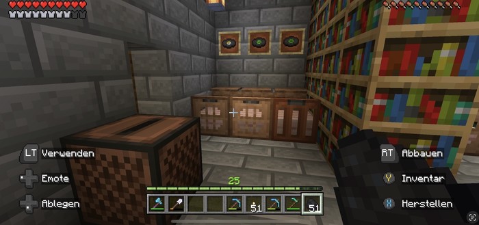 A screenshot from Minecraft showing an interior with stone walls, a turntable block, bookshelves, and item frames with vinyl records displayed within. There's a visible player's HUD including health, experience, and a hotbar with items. Game control icons and