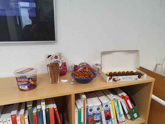 Verschiedene Süßigkeiten und Knabbersachen stehen auf einem halbhohen Bücherregal