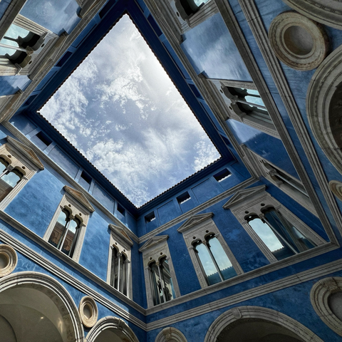 Blick in einen historischen Innenhof, ein blaues Gebäude mit blauem Himmel
