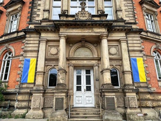 Altbau der Stabi Hamburg mit zwei ukrainischen Flaggen links und rechts des Eingangs.