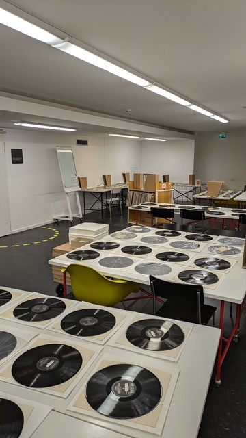 Raum, wo einzelne Schallplatten zur Trocknung auf Tischen gelagert sind.