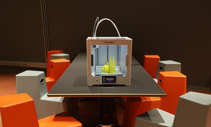 3D Drucker auf Tisch. Sitzmöglichkeiten drumherum.