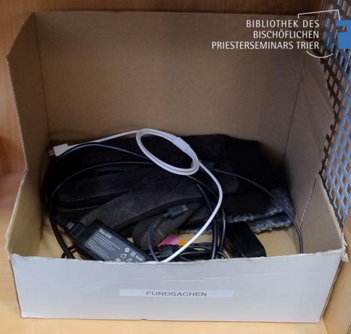 Fundsachenbox mit Inhalt: Handschuhe, Ladekabel, Earpods und anderes mehr.