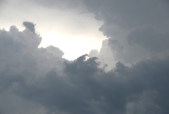 Wolken in vielen Abstufungen von Grau um eine sehr helle Bildmitte herum verteilt.