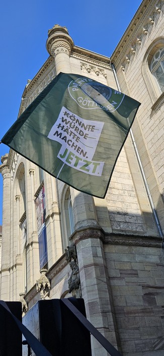 könnte würde hätte: durchgestrichen. 
Machen jetzt 
Grüne Parents for Future Göttingen Fahne vor dem Auditorium in Göttingen bei strahlend blauem Himmel. 