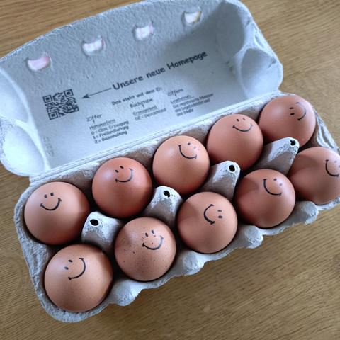 foto einer 12er-box eier, auf denen auf der nach oben zeigenden seite ein smiley aufgedruckt ist