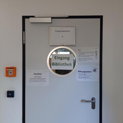 foto einer tür zu einer bibliothek, die mit vielen hinweisschildern versehen ist