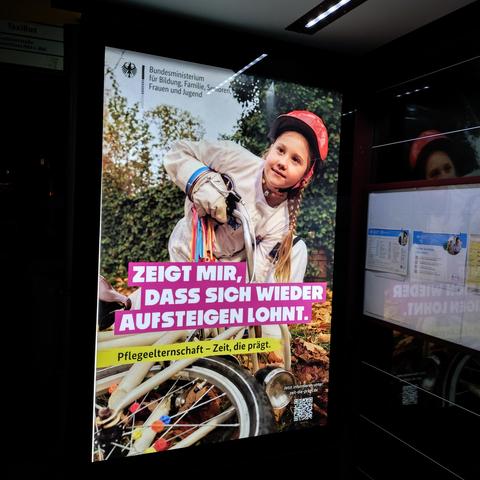 foto einer werbung des bundesministeriums für bildung, familie, senioren, frauen und jugend mit einem kind, das sich nach einem sturz mit einem fahrrad wieder aufrappelt, und den schriftzügen "zeigt mir, dass sich wieder aufsteigen lohnt." und "pflegeelternschaft – zeit, die prägt".