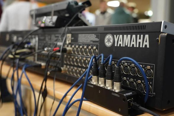 foto der rückseite eines großen mischpultes von yamaha mit einigen mikrofonkabeln
