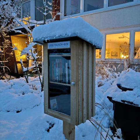 foto einer büchertauschbox in einem vorgarten mit viel schnee