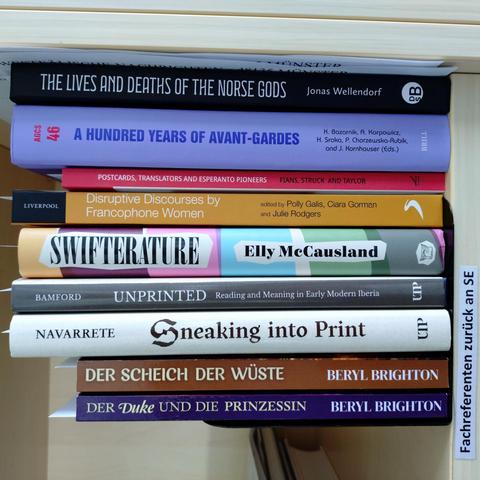 foto einiger bücher in einem regalfach; zu besseren lesbarkeit der titel auf den buchrücken wurde das foto um 90 grad nach links gedreht