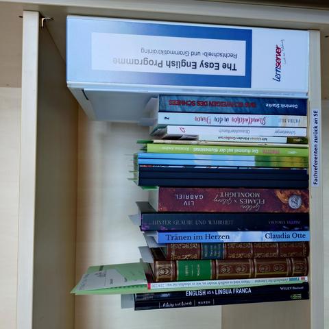 foto einiger bücher in einem regalfach; zu besseren lesbarkeit der titel auf den buchrücken wurde das foto um 90 grad nach links gedreht