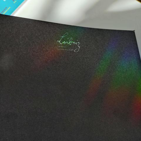 foto der rückseite des heftes 1/2026 vom leibniz-magazin mit einer licht-reflexion im schwarz-auf-schwarz-lack für das leibniz-logo