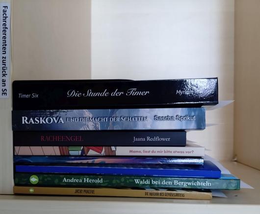 foto einiger bücher in einem regalfach; zu besseren lesbarkeit der titel auf den buchrücken wurde das foto um 90 grad nach rechts gedreht