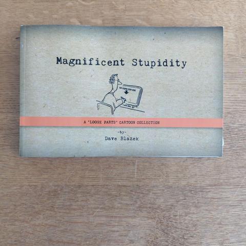 photo of the book "magnificent stupidity" by dave blazek on a wooden table