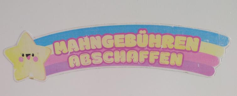 A smiling shooting star with a rainbow tail that has the inscription "Mahngebühren abschaffen" which is German for "abolish late book fines".