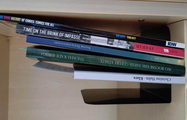 foto einiger bücher in einem regalfach; zu besseren lesbarkeit der titel auf den buchrücken wurde das foto um 90 grad nach links gedreht