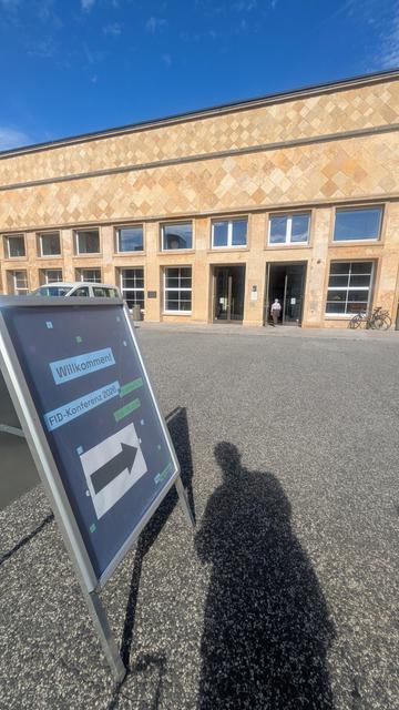 Ein Aufsteller der FID Konferenz 2026 vor dem Casino der Uni Frankfurt/ Main